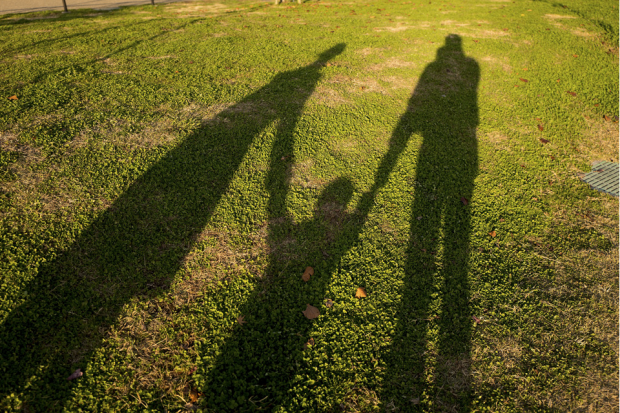 Shadows of two adults holding a child's hand.